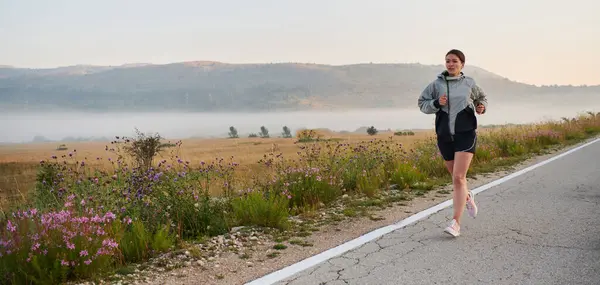 一位坚定而有进取心的运动员自信地奔向日出 体现了她清晨跑步时的决心和力量 — 图库照片