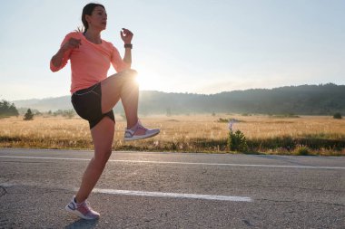 Kararlı bir atletik kadın koşudan sonra esneme hareketleri yapar, spor yolculuğuna kendini adamaya ve vücudunun esnekliğini ve esnekliğini arttırmaya çalışır.