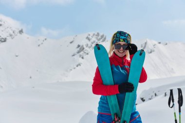 Profesyonel bir kadın kayakçı Alplerin karlı zirvelerine başarıyla tırmandıktan sonra sevinir..