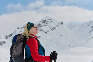 Kararlı bir kayakçı Alplerde karlı bir zirveye tırmanır, destansı bir iniş için taşıma gereçleri taşır.