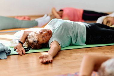 Bir grup son sınıf öğrencisi, güneş alan bir alanda eğitmenin rehberliğinde boyun, sırt ve bacak esnetme gibi çeşitli yoga egzersizleri yaparak refahı ve uyumu sağlıyorlar.. 