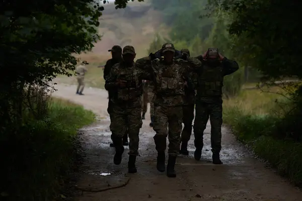 Grupa Elitarnych Żołnierzy Prowadzi Jeńców Przez Obóz Wojskowy Pokazując Napiętą — Zdjęcie stockowe