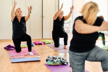 Bir grup son sınıf öğrencisi, güneş alan bir alanda eğitmenin rehberliğinde boyun, sırt ve bacak esnetme gibi çeşitli yoga egzersizleri yaparak refahı ve uyumu sağlıyorlar.. 