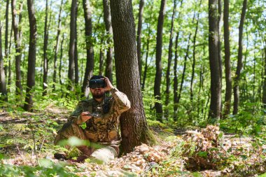 Son model VR gözlükleriyle donatılmış seçkin bir asker askeri bir drone 'u manevra yaparak modern savaş teknolojisinin kusursuz bütünleşmesini gösteriyor..