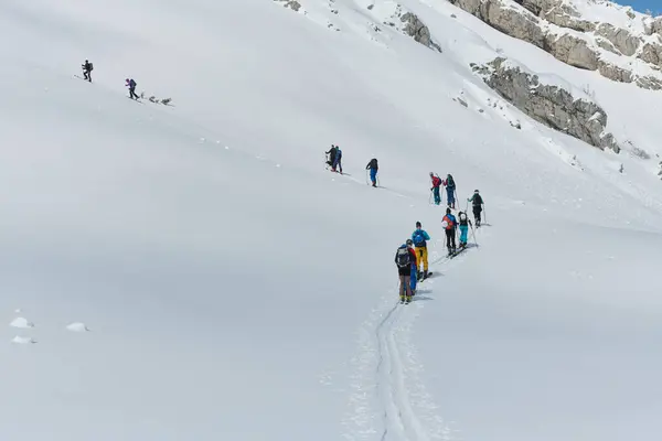 プロのスキー登山者のグループは 最先端の機器を使用して危険な雪の頂上に登ります ストックフォト