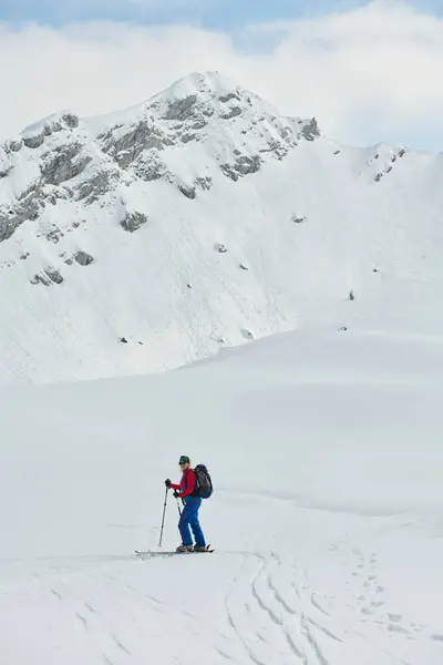 一位女滑雪者站在一座雪山的山顶上 她身穿职业装备和滑雪板 正准备欢快地滑落 — 图库照片