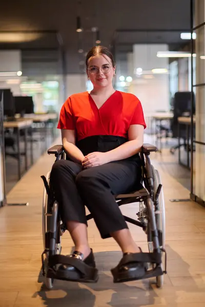 車椅子の現代の若い実業家は グラスウォールのオフィスを持つ包括的なワークスペースに囲まれ ビジネスの世界で決意と革新を体現しています ストック画像