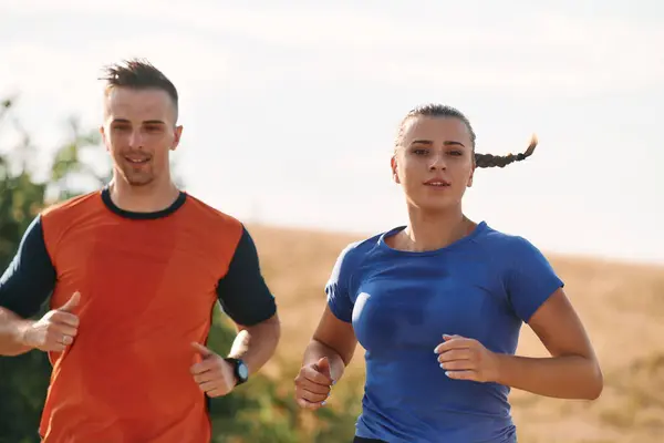 Para Ubrana Odzież Sportową Biegnie Wzdłuż Malowniczej Drogi Podczas Porannego Zdjęcia Stockowe bez tantiem