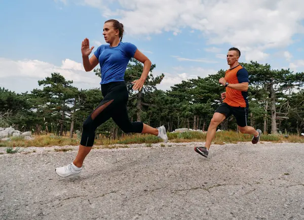 一对穿着运动服的夫妇在晨练时沿着风景秀丽的道路跑步 享受新鲜空气 保持健康的生活方式 免版税图库图片