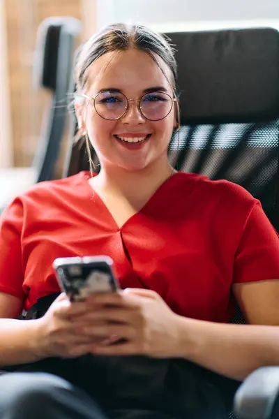 stock image A businesswoman resting on a short break from work in a modern startup coworking center, using her smartphone to unwind and recharge. 