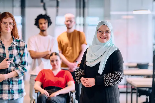 現代のスタートアップのガラス張りのオフィスで廊下を歩く若いビジネスの人々の多様なグループ 車椅子に乗っている人とヒジャーブを着ている女性を含む — ストック写真
