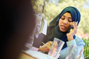 Huzurlu, Afro-Amerikalı, tesettürlü Müslüman bir kadın doğanın huzurlu güzelliğinin ortasında cep telefonuyla barışçıl bir konuşma yapar. 