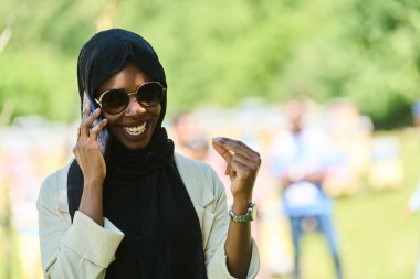  Orta Doğulu tesettürlü Müslüman kadın, küçük bir arıcılık işini yönetirken akıllı telefon kullanıyor, modern teknolojiyi geleneksel uygulamalarla harmanlıyor.