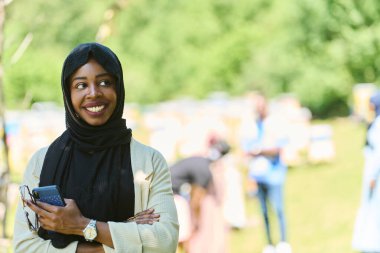  Orta Doğulu tesettürlü Müslüman kadın, küçük bir arıcılık işini yönetirken akıllı telefon kullanıyor, modern teknolojiyi geleneksel uygulamalarla harmanlıyor.