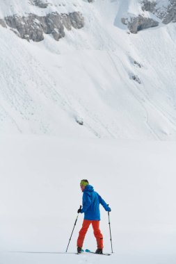 Yalnız bir kayakçı, dağların zirvesine tehlikeli bir tırmanışta elementlere göğüs gerer..
