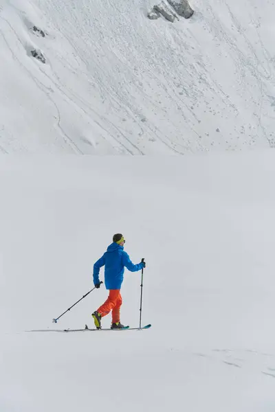 stock image A lone skier braves the elements on a perilous climb to the top of an alpine peak.