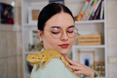 Neşeli bir anda güzel bir kadın, sevimli sakallı ejderha evcil hayvanlarıyla poz veriyor, sevgi ve arkadaşlık yayıyor..