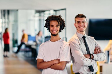 Aralarında Afro-Amerikalı bir işadamı ve gömlek ve kravat takmış genç bir liderin de bulunduğu bir grup meslektaşı, dinamik bir karışımı temsil eden modern bir çalışma merkezi ofisinde birlikte poz veriyorlar.