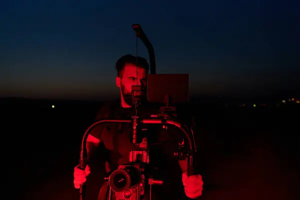 stock image A skilled videographer captures the intensity of athletes running, illuminated by vibrant red lights, encapsulating the energy and determination of their nighttime training session.