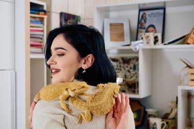 Neşeli bir anda güzel bir kadın, iki sevimli sakallı ejderha evcil hayvanıyla poz veriyor, sevgi ve arkadaşlık yayıyor..