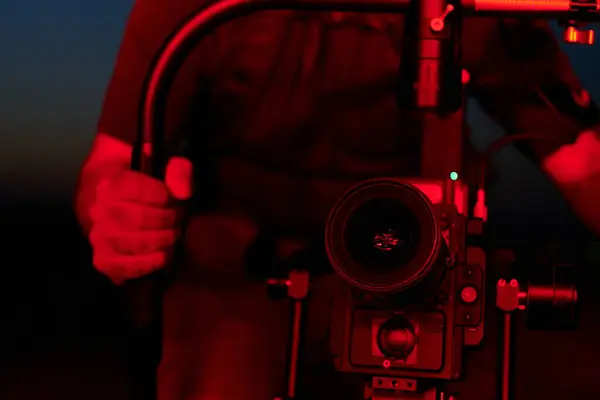 stock image A skilled videographer captures the intensity of athletes running, illuminated by vibrant red lights, encapsulating the energy and determination of their nighttime training session.