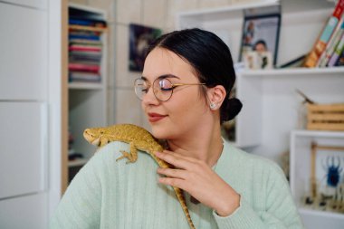 Neşeli bir anda güzel bir kadın, sevimli sakallı ejderha evcil hayvanlarıyla poz veriyor, sevgi ve arkadaşlık yayıyor..