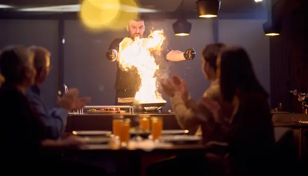 Stock image In a restaurant setting, a professional chef presents a sizzling steak cooked over an open flame, while an European Muslim family eagerly awaits their iftar meal during the holy month of Ramadan