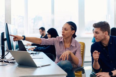 Ofiste yapılan beyin fırtınası sırasında çok kültürlü genç iş adamlarının ortak çalışma süreci. Resmi olarak giyinmiş çeşitli gençler tasarım projesinin geliştirilmesinde işbirliği yapıyor.