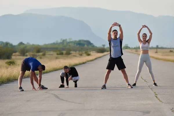 stock image A determined group of athletes engage in a collective stretching session before their run, fostering teamwork and preparation in pursuit of their fitness goals.