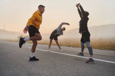 Hareketli ve çeşitli bir grup sporcu esneme ve ısınma egzersizleriyle meşgul, birliklerini ve hareketli bir sabah koşusuna hazır olduklarını gösteriyorlar..