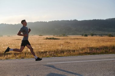 Atletik bir adam koşarken kararlılığını sergiler, sağlıklı bir yaşam tarzına ve yaklaşan maraton yarışmasına hazırlanmaya bağlıdır.