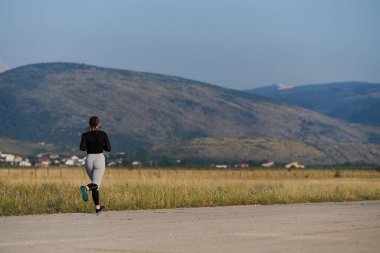 Atletik bir kadın sağlıklı bir yaşam tarzında özgürlük ve neşe bulur. Gün doğumunda güzel bir patikada koşar.. 
