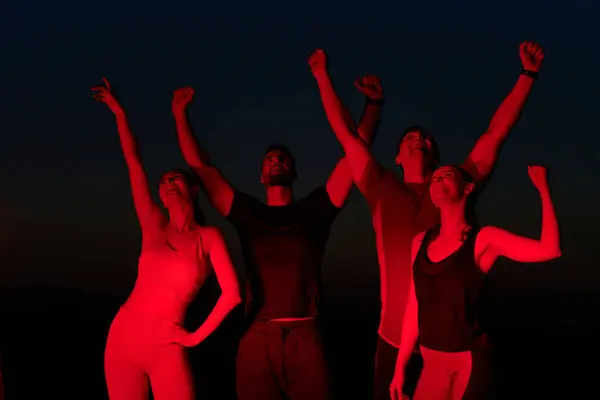 stock image In the late hours of the night, a jubilant group of friends celebrates with cheers and embraces, reveling in the shared success of completing a long marathon.