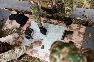 İyi eğitimli bir askeri birlik, bir brifing sırasında askeri harita incelerken stratejik bir görev planlar ve organize eder.. 