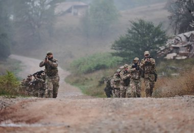 Disiplinli ve özel bir askeri birlik, kamuflajlı, stratejik devriye gezen ve yüksek bahisli bir ortamda kontrolü elinde tutan, hassasiyetlerini, birliklerini ve hazırlıklarını gösteren