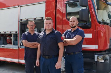 Yetenekli ve kendini işine adamış bir itfaiye ekibi sanat eseri itfaiye arabalarının önünde gururla poz vererek modern ekipmanlarını ve kamu güvenliğini sağlama kararlılıklarını sergiliyor.