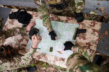 İyi eğitimli bir askeri birlik, bir brifing sırasında askeri harita incelerken stratejik bir görev planlar ve organize eder.. 