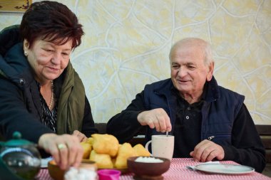 Yaşlı bir çift, sakin bir sabahta bir fincan kahvenin tadını çıkarırken, kırsal alanlarının etrafını saran doğanın huzurlu güzelliğine dalmış bir şekilde saf neşe buluyor.. 