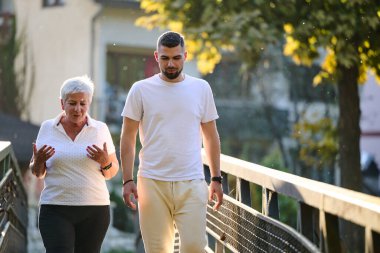 Yakışıklı bir adam ve yaşlı bir kadın doğada huzurlu bir yürüyüş yapar, çarpıcı bir günbatımının zeminine karşı güzel bir köprüyü geçer, sağlıklı ve canlı nesiller arası kavramı somutlaştırır.