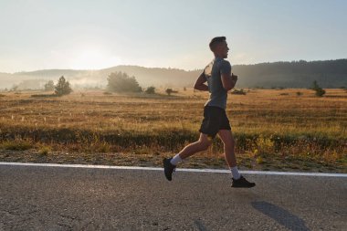 Atletik bir adam koşarken kararlılığını sergiler, sağlıklı bir yaşam tarzına ve yaklaşan maraton yarışmasına hazırlanmaya bağlıdır.