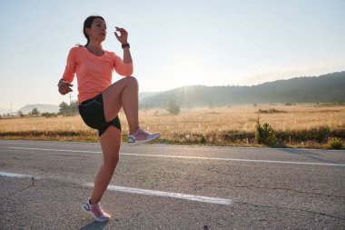  Kararlı bir atletik kadın koşudan sonra esneme hareketleri yapar, spor yolculuğuna kendini adamaya ve vücudunun esnekliğini ve esnekliğini arttırmaya çalışır.