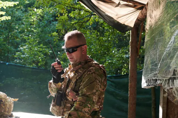 stock image A military major employs a Motorola radio for seamless communication with his fellow soldiers during a tactical operation, showcasing professionalism and strategic coordination. 