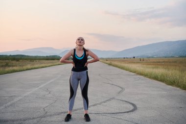 Bir kadın sporcunun dinlenirken, yoğun bir koşunun ardından terleyerek, azim ve kondisyonuna olan bağlılığını somutlaştıran, kendini adamış bir kadın sporcunun nadide görüntüsünü yakına çekiyoruz.