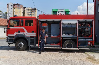 A dedicated firefighter preparing a modern firetruck for deployment to hazardous fire-stricken areas, demonstrating readiness and commitment to emergency response.  clipart