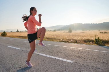  Kararlı bir atletik kadın koşudan sonra esneme hareketleri yapar, spor yolculuğuna kendini adamaya ve vücudunun esnekliğini ve esnekliğini arttırmaya çalışır.