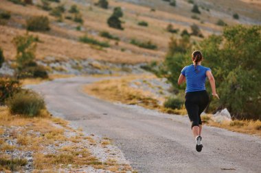 Kararlı bir bayan atlet gün doğumunda ormanda koşuyor, nefes kesici doğal güzellik ve canlı yeşillik ile çevrili.. 