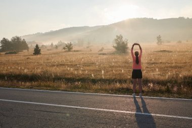  Kararlı bir atletik kadın koşudan sonra esneme hareketleri yapar, spor yolculuğuna kendini adamaya ve vücudunun esnekliğini ve esnekliğini arttırmaya çalışır.