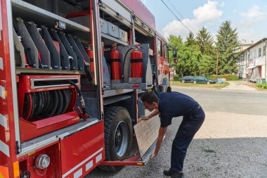 Kendini adamış bir itfaiyeci, tehlikeli bölgelerde konuşlanmak üzere modern bir itfaiye aracı hazırlıyor.. 