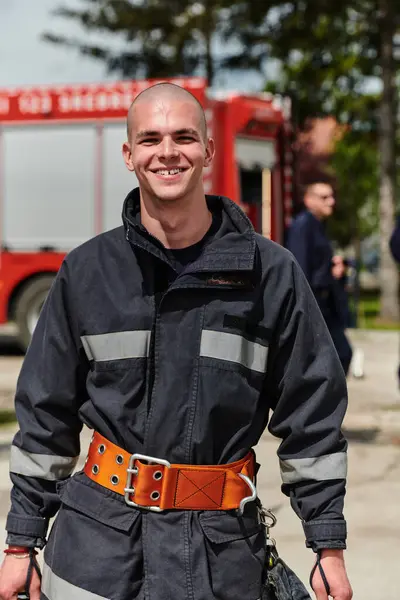 stock image A firefighter, adorned in professional gear, stands confidently beside a fire truck following a grueling firefighting training session 
