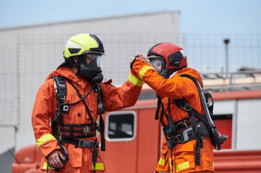Üniformalarıyla süslenmiş itfaiye teşkilatı, zafer dolu selamlar ve tezahüratlarla dolu kalpten bir kutlamaya girişiyor. Başarılı olanın ardından gelen neşe ve minnettarlığı somutlaştırıyor.